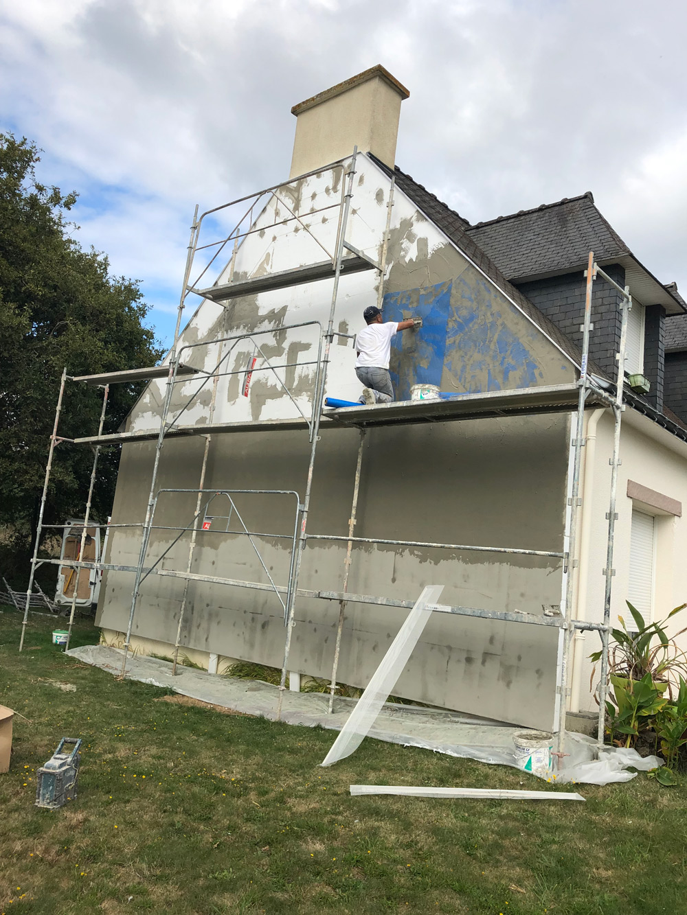 Artisan appliquant une finition sur une façade de maison